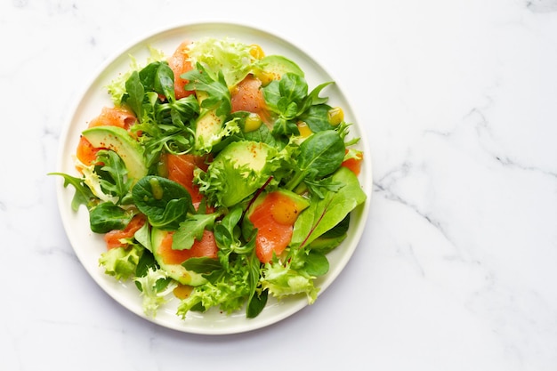 Zalm avocado en diverse slasalade op witte marmeren achtergrond