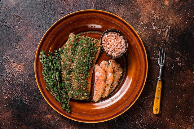 Zalm Gravlax genezen met dille en roze zout op rustieke plaat. Donkere achtergrond. Bovenaanzicht.