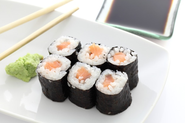 Zalm Maki sushi met stokjes en sojasaus in wit