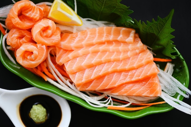 Zalm sashimi voedsel zalmfilet Japans menu met shiso perilla blad citroenkruid en specerijen verse rauwe zalmvis voor het koken van voedsel zeevruchten zalmvis met saus en wasabi bovenaanzicht