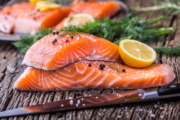 Zalm vis... Rauwe zalmfilet peper zout dille citroen rozemarijn op houten tafel.