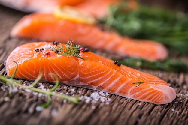 Zalm vis... Rauwe zalmfilet peper zout dille citroen rozemarijn op houten tafel.