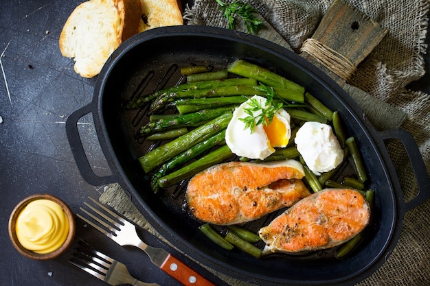 Zalm vis steak gegrild met asperges gepocheerd ei in een koekenpan Bovenaanzicht