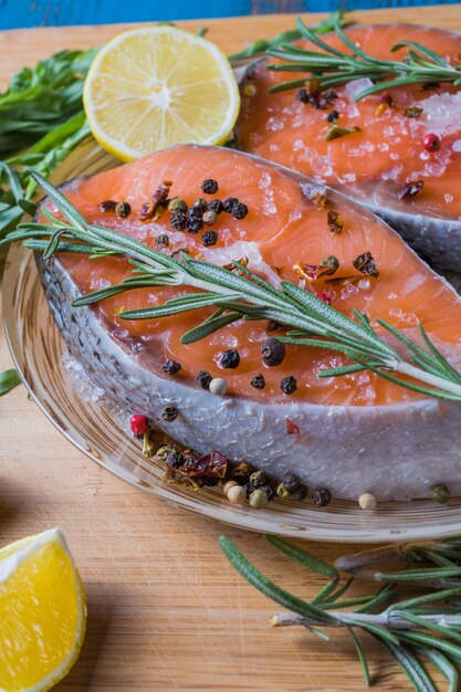 Zalm vissen op een bord met kruiden, olijfolie en citroen voor het koken, plat.