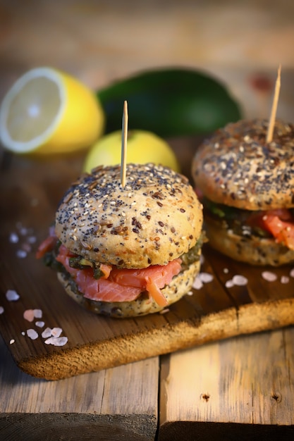 Zalmburgers met avocadopasta op gezonde broodjes met zaden.