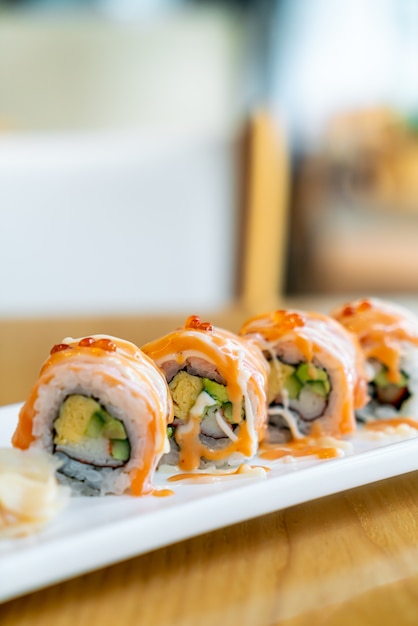 Zalmrolletjes sushi met saus bovenop - japans eten