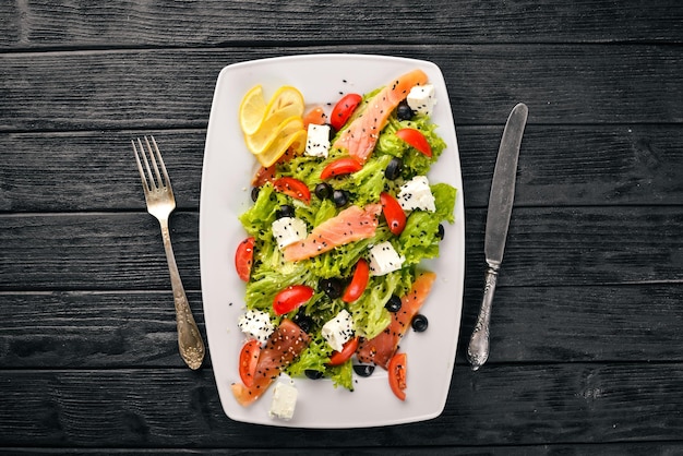 Zalmsalade feta kaas salade bladeren en verse groenten op de plaat Op een houten achtergrond Bovenaanzicht Vrije ruimte voor tekst