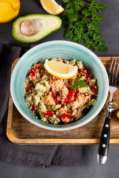 Zalmsalade met tomaten, avocado en quinoa in een blauwe kom op een donkergrijze tafel verticale foto a