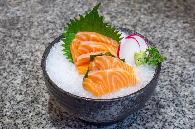 Zalmsashimi op ijs in zwart kom Japans voedsel