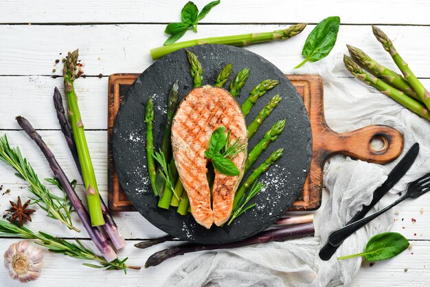 Zalmsteak met gebakken asperges en kruiden op een zwarte stenen plaat Bovenaanzicht Vrije ruimte voor uw tekst