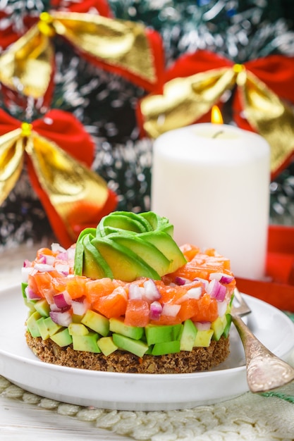 Zalmtartaar (forel) met avocado en rode ui op roggebrood. Voorgerecht voor Kerstmis en Nieuwjaar