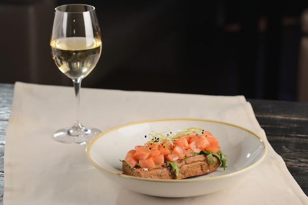 Zalmtartaar met rucola op een stuk brood. In een witte plaat