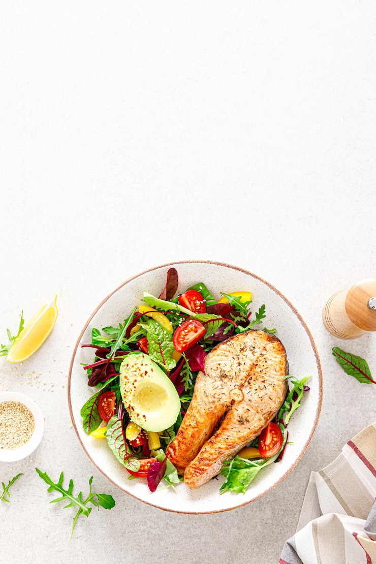 Foto zalmvissteak gegrilde avocado en verse groentesalade met tomatenpaprika en bladgroenten bovenaanzicht