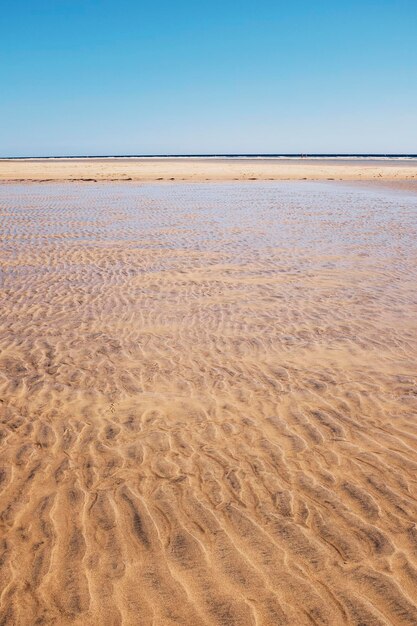 Zand- en strandlandschap met transparant schoon tropisch oceaanwater Blauwe lucht op de achtergrond