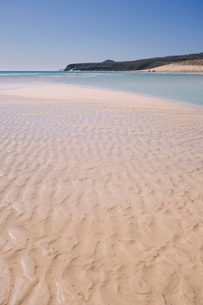 Zand- en strandlandschap met transparant schoon tropisch oceaanwater Blauwe lucht op de achtergrond