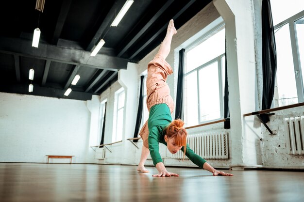 Zand op handen. Professionele yogacoach met een haarknot die er geconcentreerd uitziet terwijl ze op haar handen staat