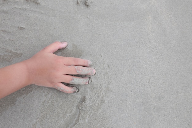 Zand op het strand en de hand van het kind.