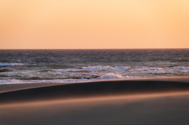 Zandduinen en kust tijdens zonsondergang Zomerlandschap in de woestijn Warm weer Lijnen in het zand Landschap zonder mensen