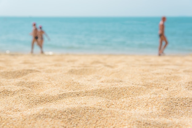 Zandige strandclose-up met erachter onduidelijk beeld blauwe overzees