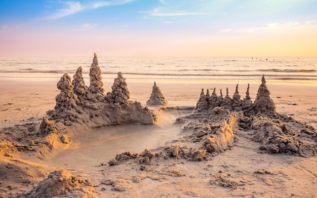 Zandkasteel op het strand met opwarmend licht en prachtige zonsonderganghemel in de zomervakantie