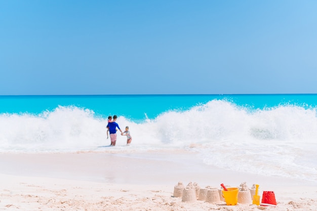 Zandkasteel op wit tropisch strand met plastic kinderspeelgoed