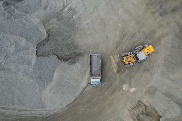 Zandladers scheppen stenen in dumptrucks
