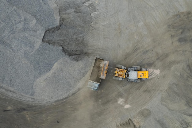 Zandladers scheppen stenen in dumptrucks