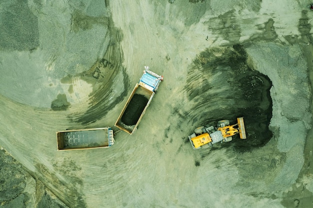 Zandladers scheppen stenen in dumptrucks