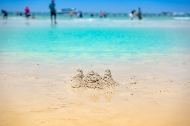 Zandstapel voor spel op strand en groene overzees in de zomer