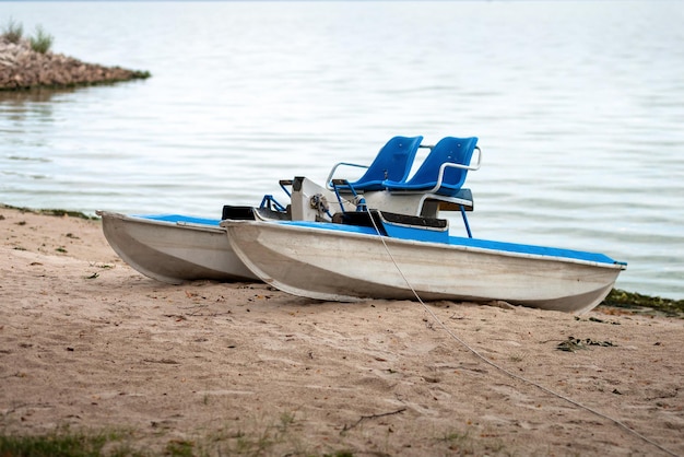 Zandstrand met een oude catamaran Verlaten waterattractie