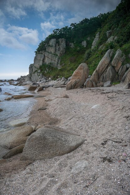 Foto zandstrand met grote rotsblokken, kliffen aan de oever en helder water