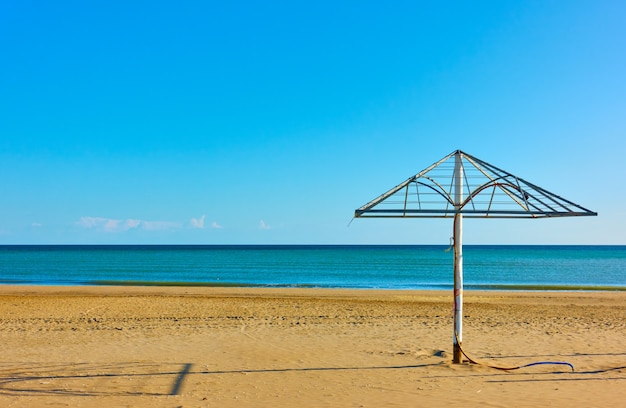 Zandstrand met oude parasol in Rimini aan de kust van de Adriatische zee, Italië