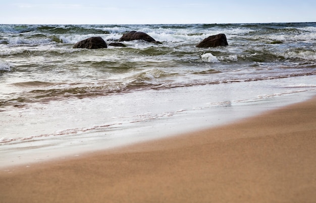 Zandstrand zee met schuim en golven van winderig weer