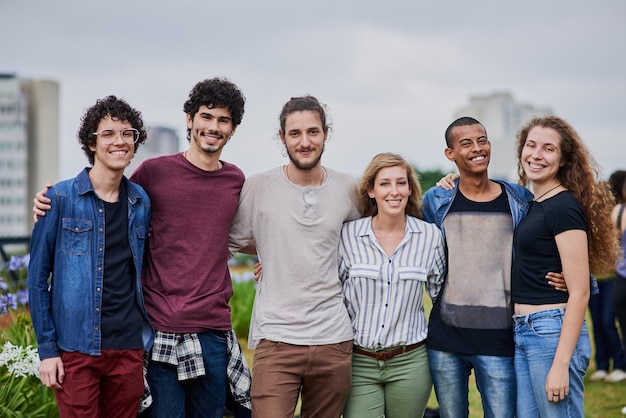 Ze hebben een mooie toekomst voor zich Portret van een groep jonge studenten die overdag buiten in een park armen om elkaar heen staan