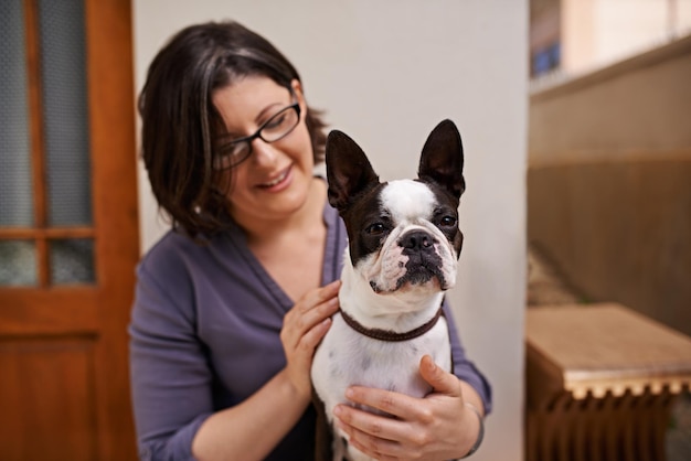 Ze heeft veel aandacht nodig Een vrouw van middelbare leeftijd die met haar hond op een bankje voor haar huis zit