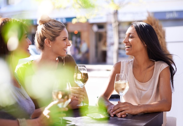 Ze is een beetje een wijnkenner Bijgesneden opname van drie vrouwen die genieten van een glas witte wijn in een café op de stoep