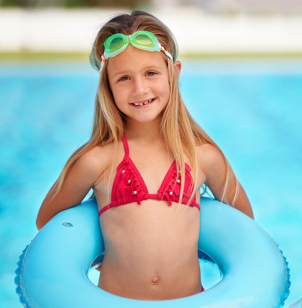 Ze is een zomerkind een schattig klein meisje dat een opblaasbaar zwembad gebruikt tijdens het zwemmen