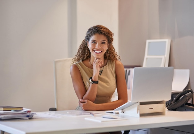 Ze klaart de klus altijd met een glimlach Portret van een zakenvrouw die aan haar bureau op een laptop werkt