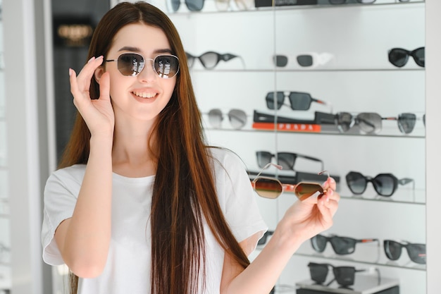 Ze maakte haar keuze Mooie jonge vrouw die haar nieuwe zonnebril aanpaste en glimlachte terwijl ze in de optiekwinkel stond