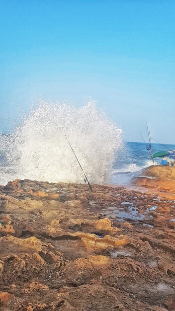 Foto zee golven spetteren op de kust tegen een heldere blauwe hemel