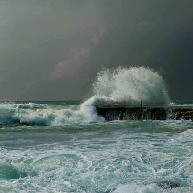 Zee golven spetteren op de pier tegen bewolkte lucht