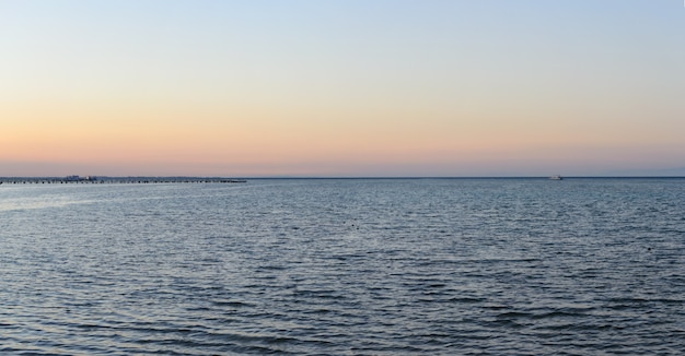 Zee kust jacht op de horizon en pier in de avond panorama