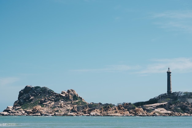 Zee natuur panoramisch uitzicht landschap achtergrond Oceaan rotsachtige kliffen bebost eiland Heldere blauwe lucht Vuurtoren op de bergtop Signaal waarschuwen zeilers schipbreuk reizen concept hoop doel van het leven