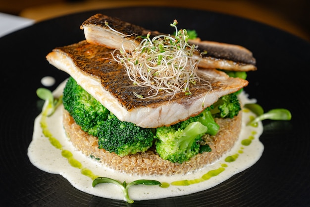 Zeebaarsfilet met broccoli en quinoa op zwarte plaat