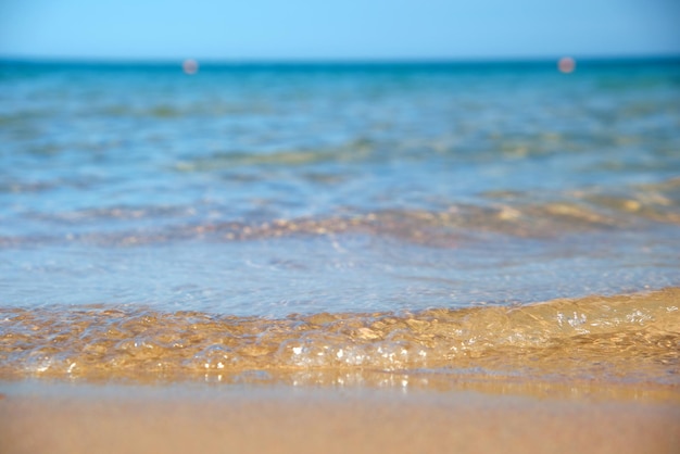 Zeegezicht met oppervlak van blauw zeewater met kleine rimpelgolven die op geel zandstrand beuken Reis- en vakantieconcept