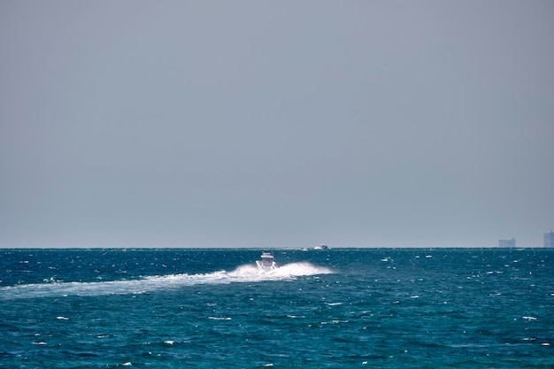 Zeegezicht met rimpelend oppervlak van blauw zeewater met witte speedboot die snel zwemt op kalme golven