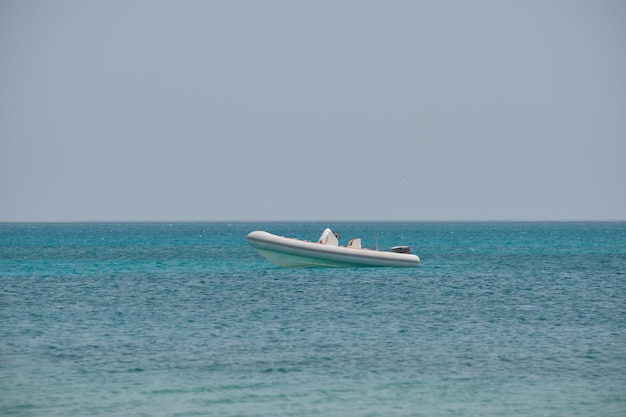 Zeegezicht met rimpelend oppervlak van blauw zeewater met witte speedboot op anker drijvend op kalme golven