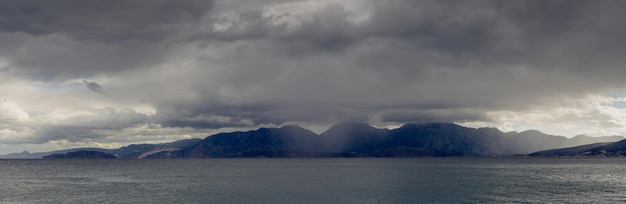 Zeegezicht Uitzicht op de stormachtige zeewolken en bergen in de verte