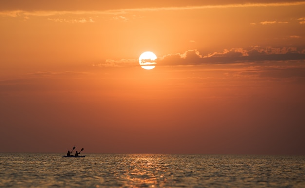 Zeegezicht van nog steeds zeeoppervlak, mannen op boot en gouden zonsondergang in de hemel