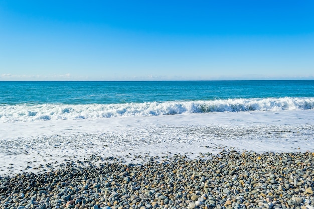 Zeegolven breken op een steenachtig strand en vormen sprays en spatten